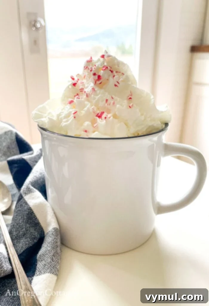 Effortless Peppermint Mochas: Giftable & Healthier Homemade Delights 2 A beautiful peppermint mocha, topped with generous whipped cream and crushed peppermint, served in a white ceramic mug, inviting a cozy winter ambiance.