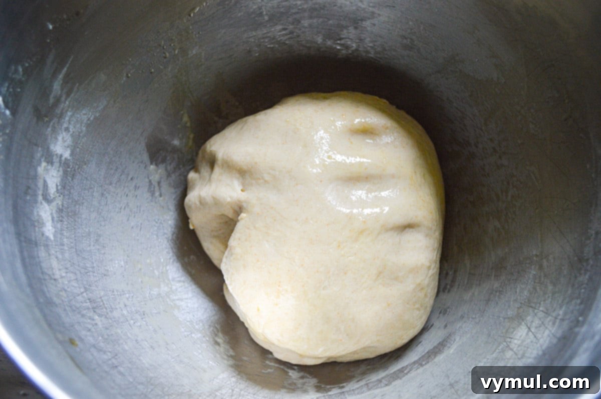 rising monkey bread dough in mixing bowl, covered with plastic wrap