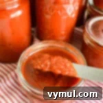 Simple Homemade Pizza Sauce for Canning Fresh or Frozen Tomatoes 12 thick pizza sauce on knife over jar