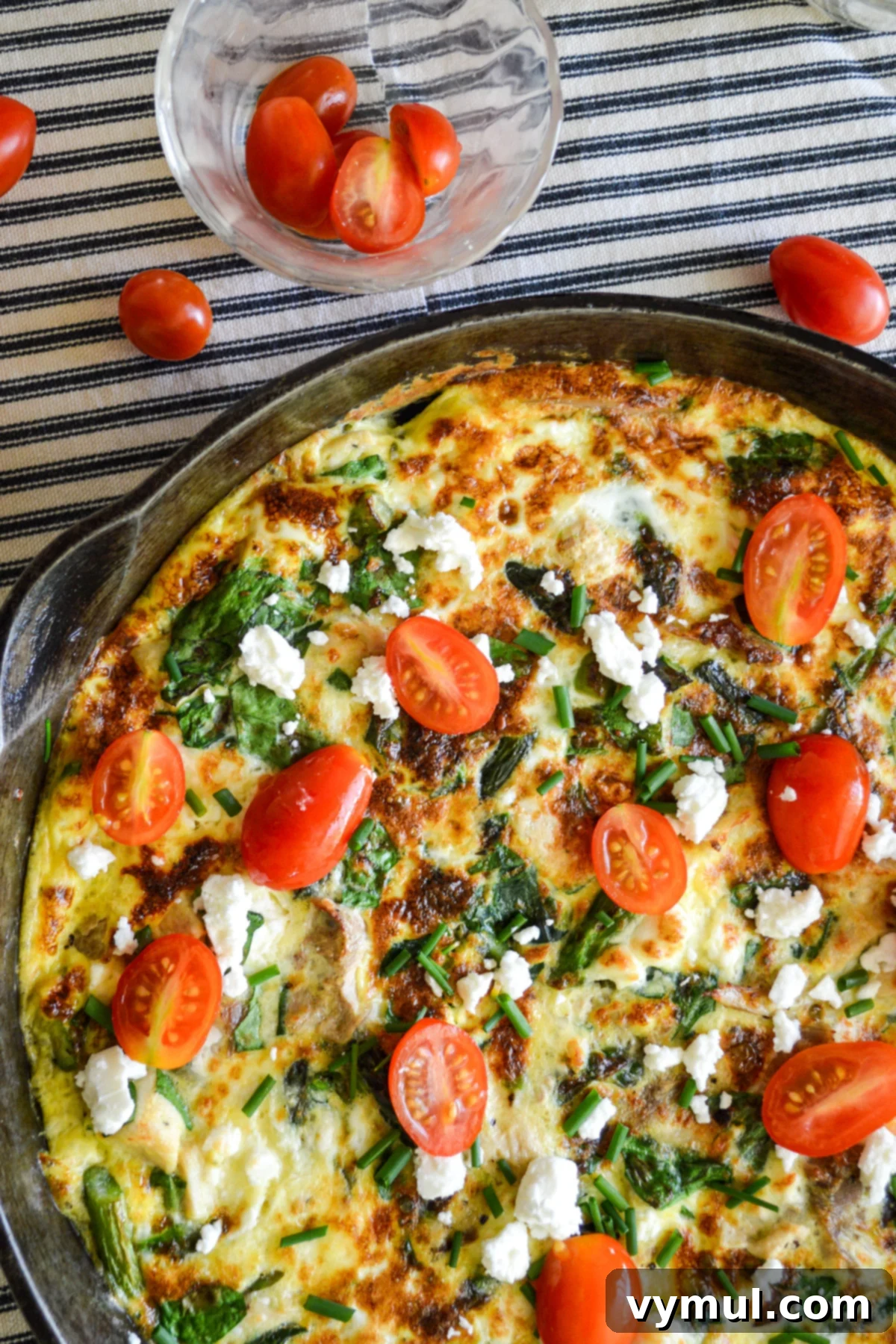 Cooked chicken spinach frittata in pan above with tomatoes