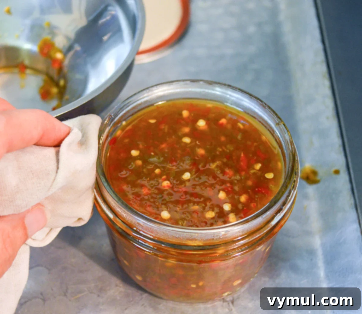 wiping rim of canning jar full of pepper jelly