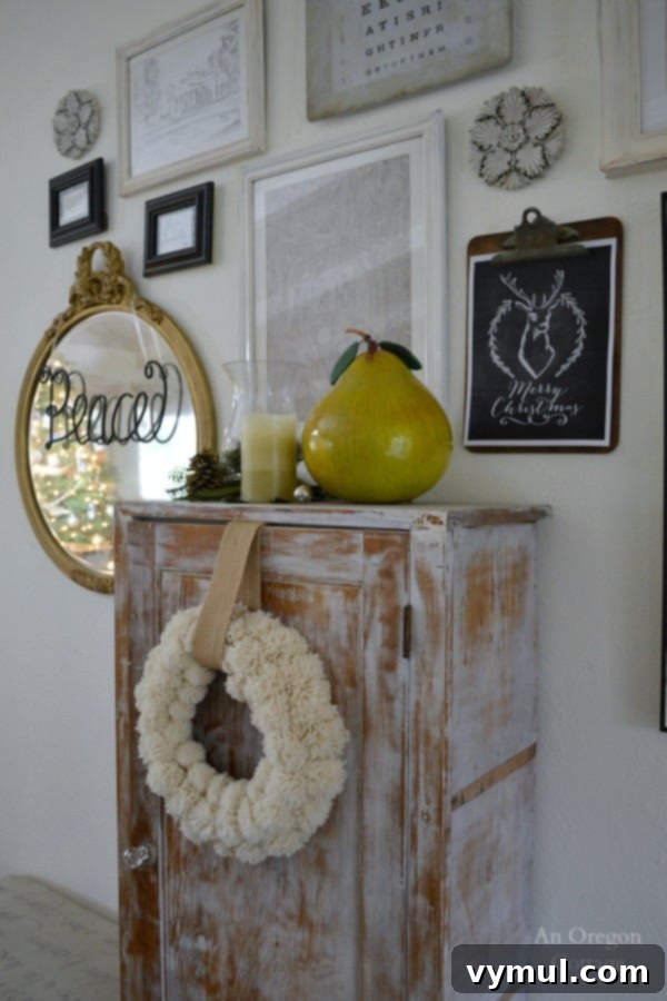 A Cozy Cottage Christmas 2014 5 Gallery wall decorated for Christmas with a DIY pom pom wreath and festive artwork