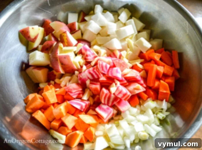 Diced root vegetables, including carrots, potatoes, and beets, in a silver mixing bowl