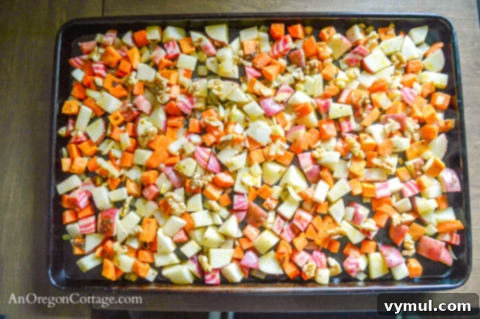 Diced root vegetables spread in a single layer on a parchment-lined baking sheet