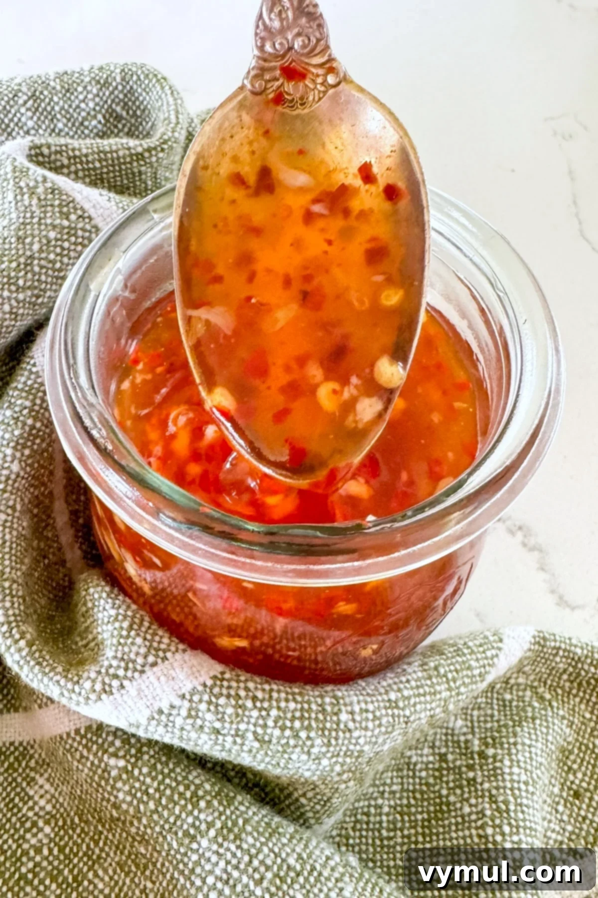 sweet chili sauce on a spoon over a jar