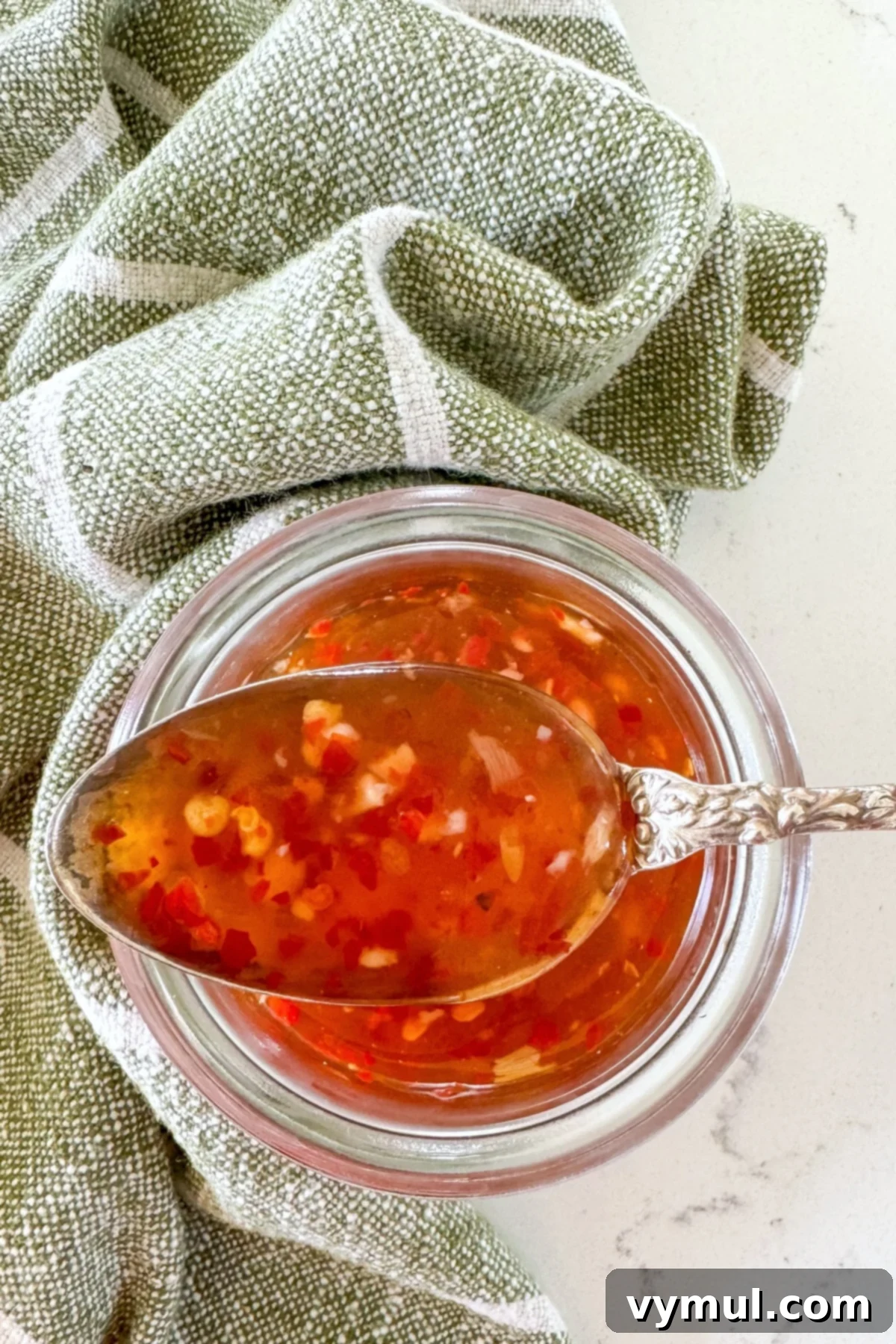 sweet chili sauce on small spoon over jar