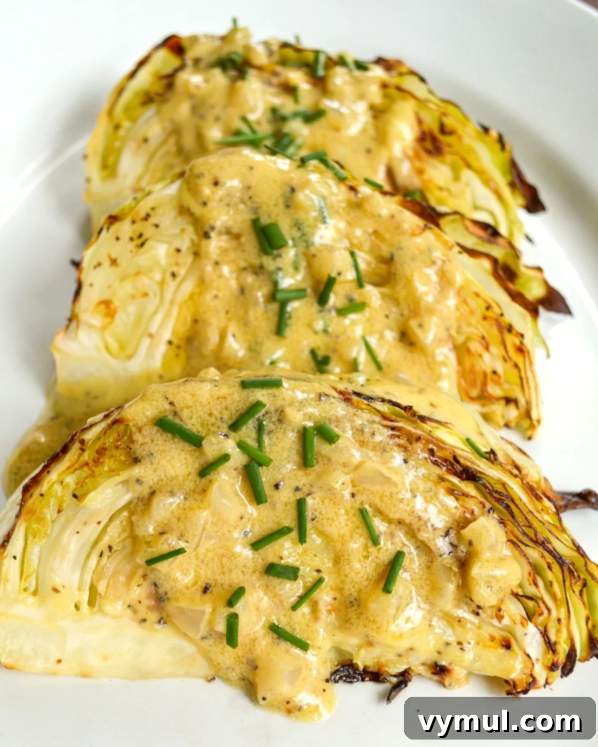 Golden Roasted Cabbage with Zesty Onion Dijon Sauce 9 Roasted cabbage on a white plate with sauce, photographed in 2015, showing a slightly separated sauce.