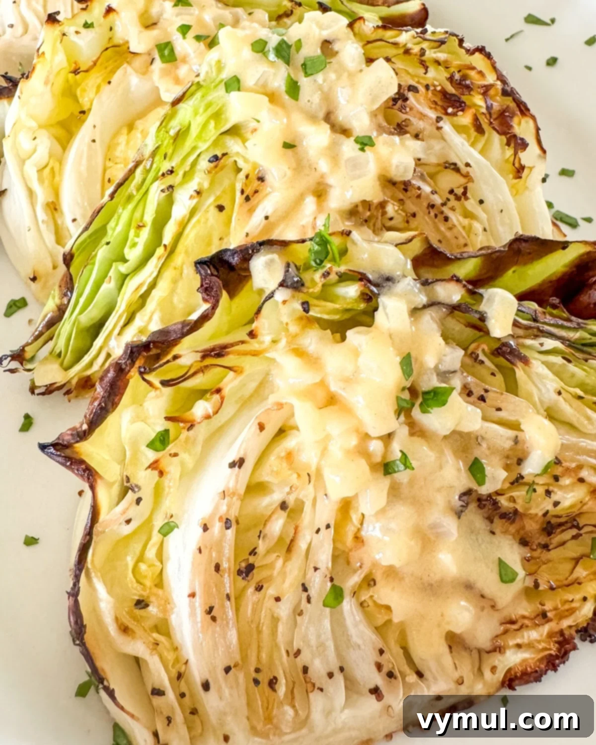 Golden Roasted Cabbage with Zesty Onion Dijon Sauce 10 Roasted cabbage on a white plate with sauce, photographed in 2025, showing a richer, more incorporated sauce.