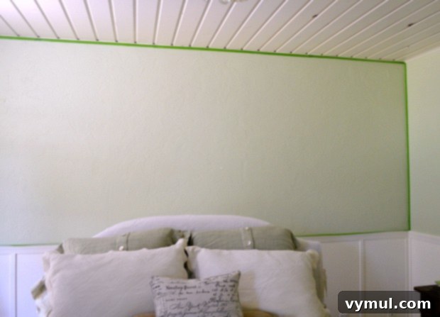 Preparing the wall for stenciling by taping the edges with painter's tape