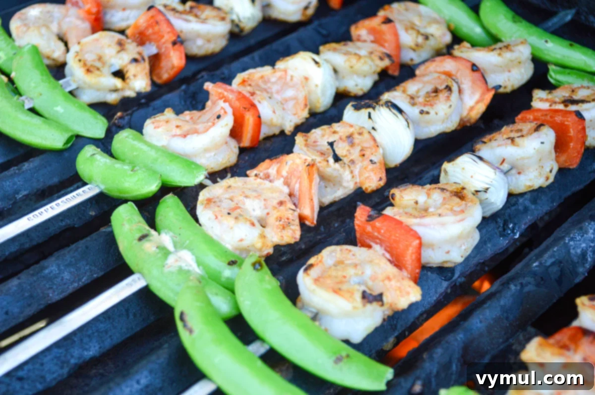Assorted shrimp and vegetable skewers sizzling on a hot outdoor grill, showing char marks and vibrant colors.