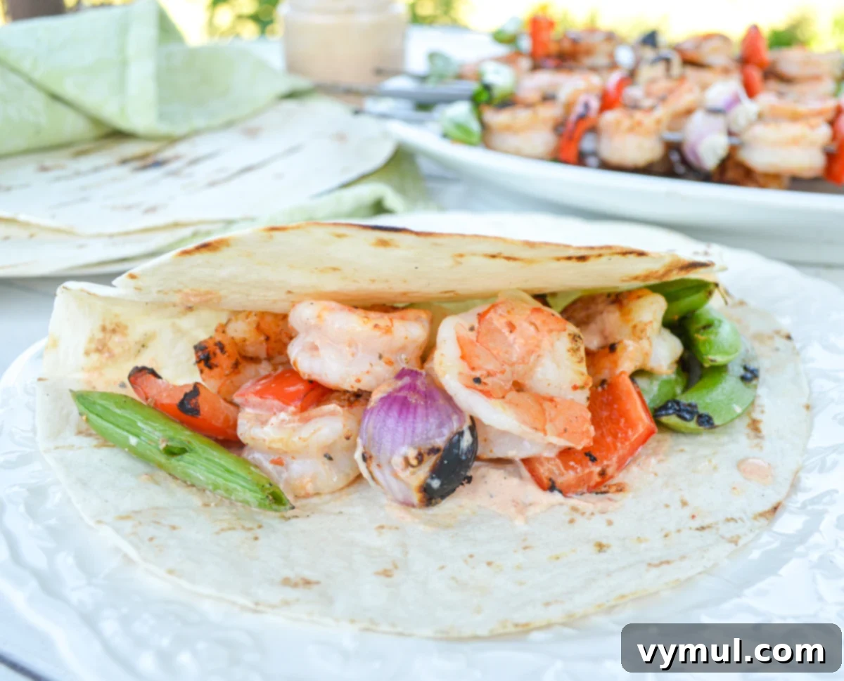 A delicious grilled shrimp taco nestled in a flour tortilla, topped with colorful vegetables and sauce, ready to eat.