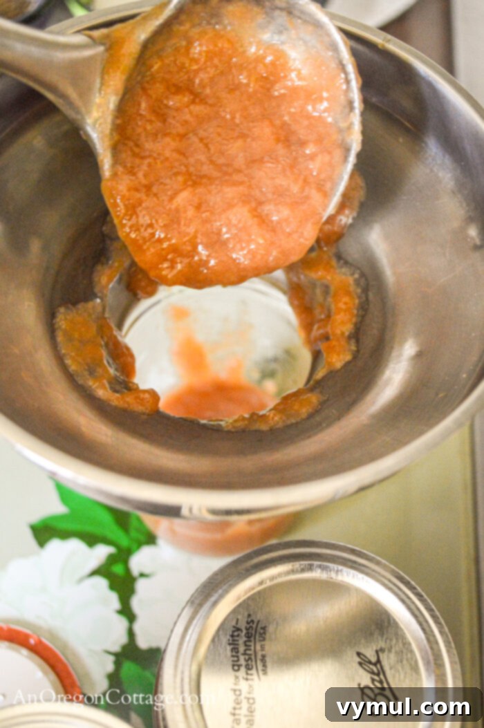 Handcrafted Honey Rhubarb Ginger Preserve 5 Pouring hot honey rhubarb ginger jam into sterilized half-pint jars using a ladle