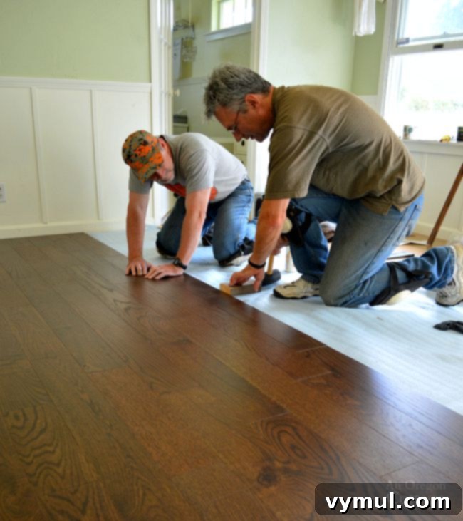 Laying an engineered hardwood floating floor, showing a person working