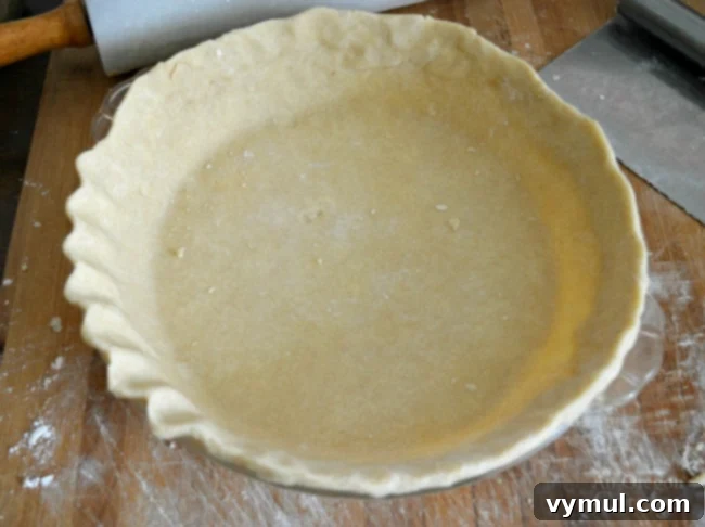 Shaping and fluting the edges of a homemade pie crust for a decorative finish.