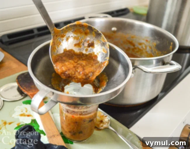 Spicy Rhubarb Chutney: Sweet Heat for Your Shelf 8 Laddling hot rhubarb chutney into a canning jar using a funnel.