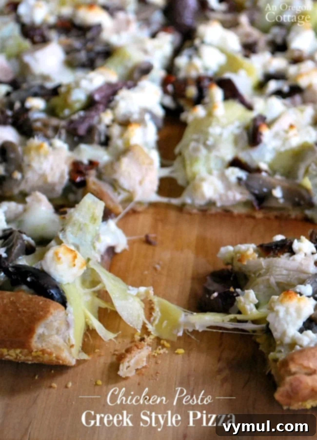 Delicious Homemade Greek Style Chicken Pesto Pizza cut into slices on a wooden board, garnished with fresh basil