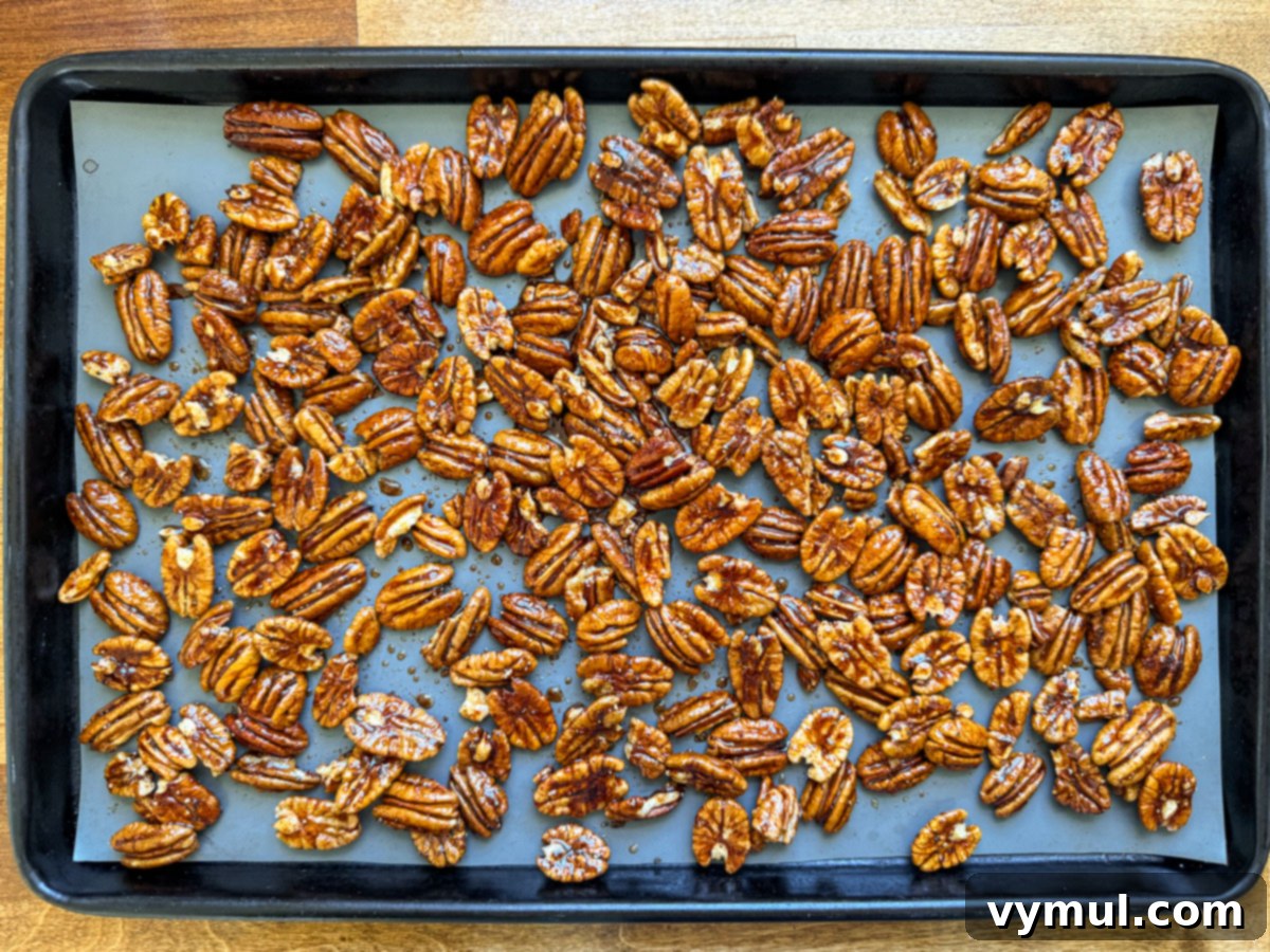 candied pecans spread in a single layer on a baking sheet lined with parchment paper