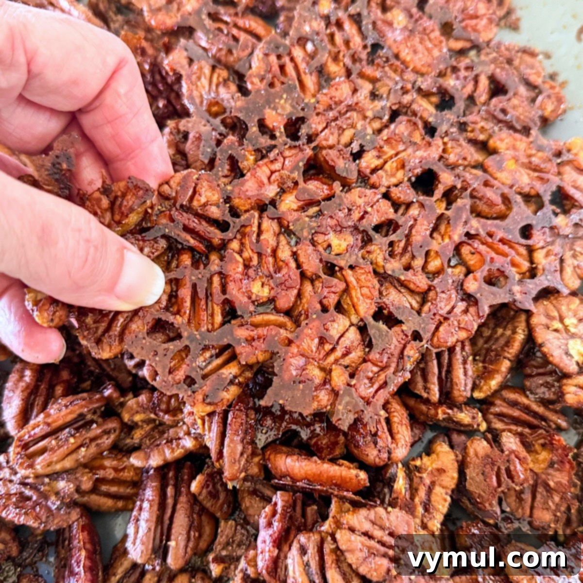 breaking apart cooled maple candied pecans by hand after baking
