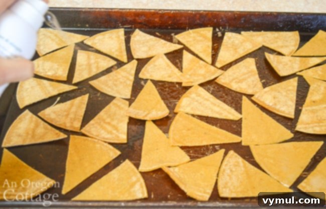 Homemade Crispy Tortilla Chips in Just 10 Minutes 4 Spraying cut tortilla triangles with olive oil on a baking sheet before baking.