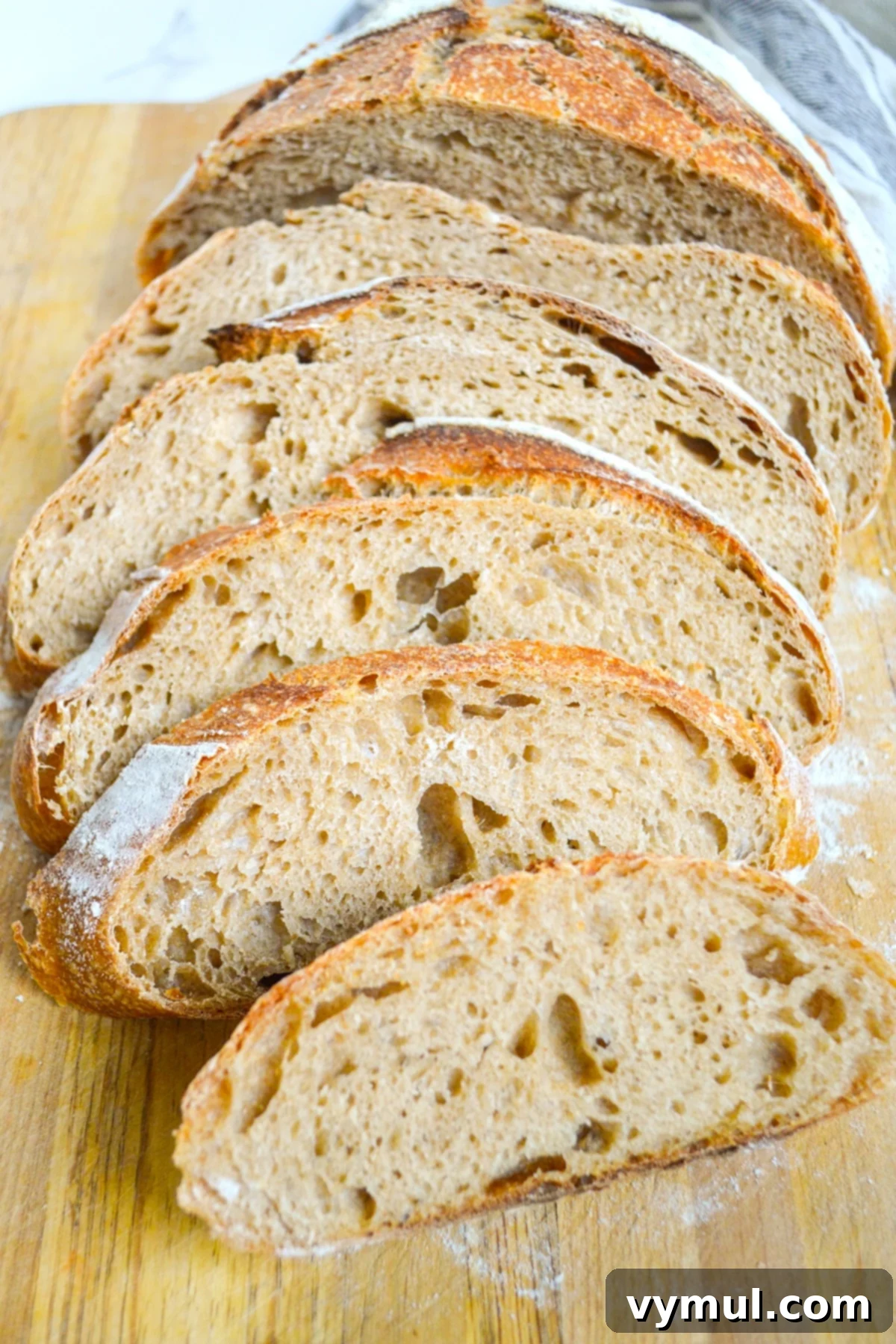 The One-Day Sourdough Secret: Artisan Bread Made Simple 2 sliced sourdough artisan bread loaf on cutting board, revealing a tender, airy interior