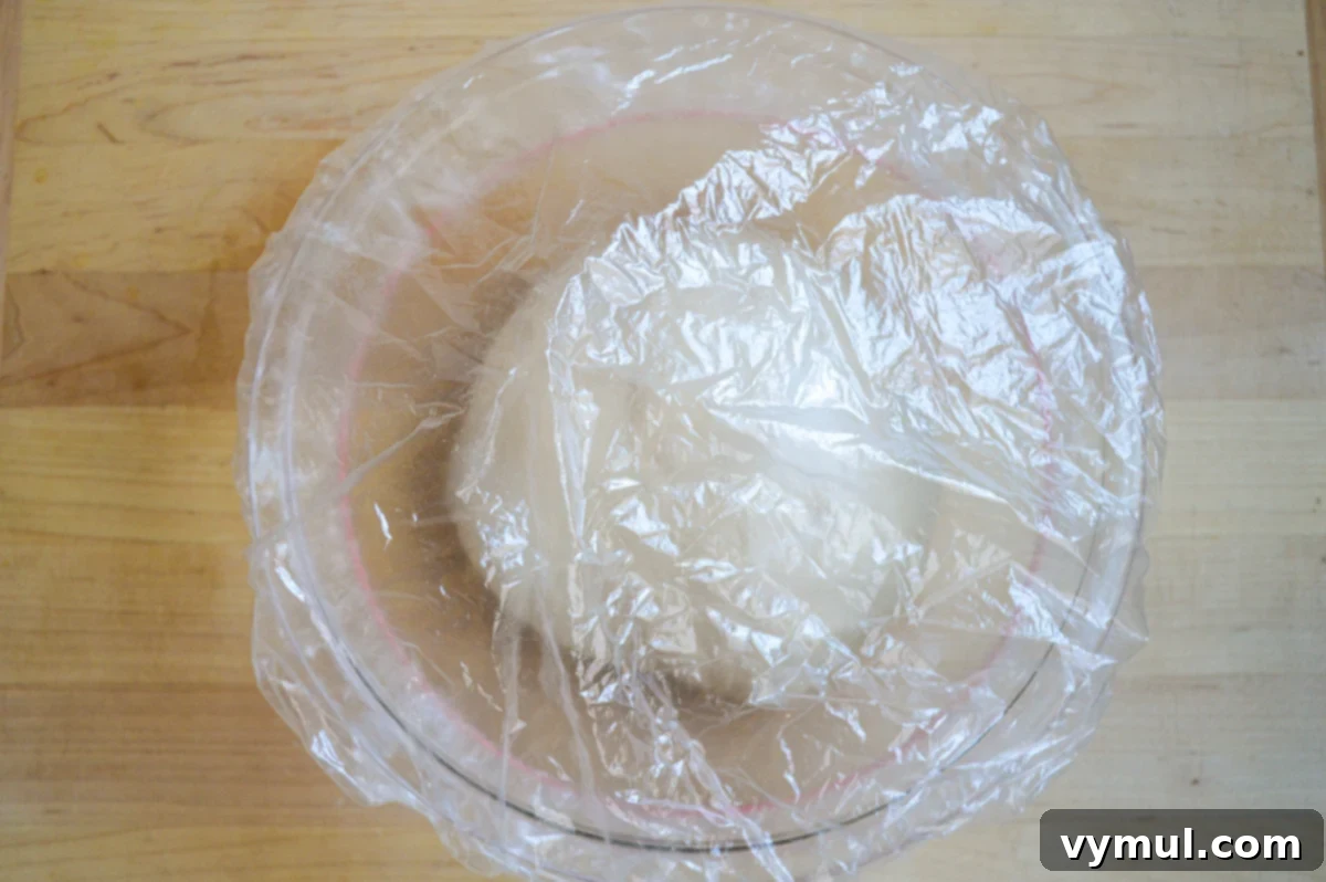 The One-Day Sourdough Secret: Artisan Bread Made Simple 7 sourdough bread dough in glass bowl, covered with plastic for its first rise