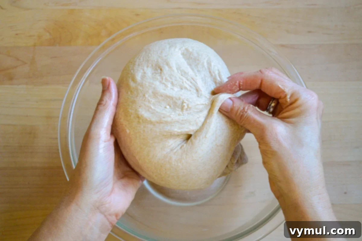The One-Day Sourdough Secret: Artisan Bread Made Simple 9 folding and shaping artisan dough over a bowl, preparing for the second rise