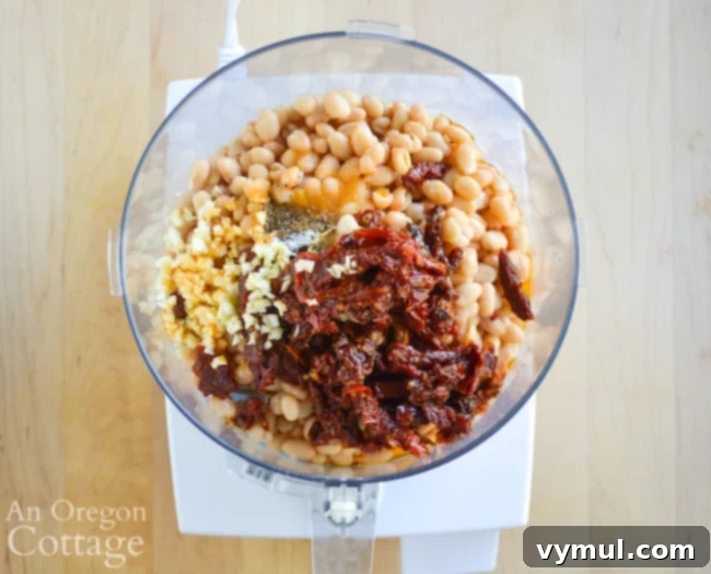 White bean dried tomato dip ingredients being processed in a food processor.