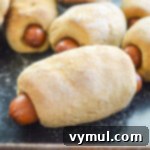 Easy 1-Hour Homemade Pigs In a Blanket 11 Freshly baked pigs in a blanket on a baking sheet, golden and inviting.