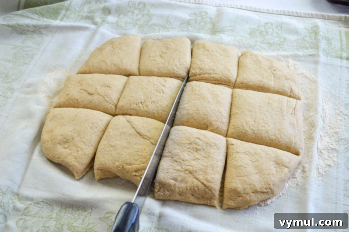 Easy 1-Hour Homemade Pigs In a Blanket 5 Homemade dough rolled out on a floured towel and cut into squares, preparing for wrapping hot dogs.