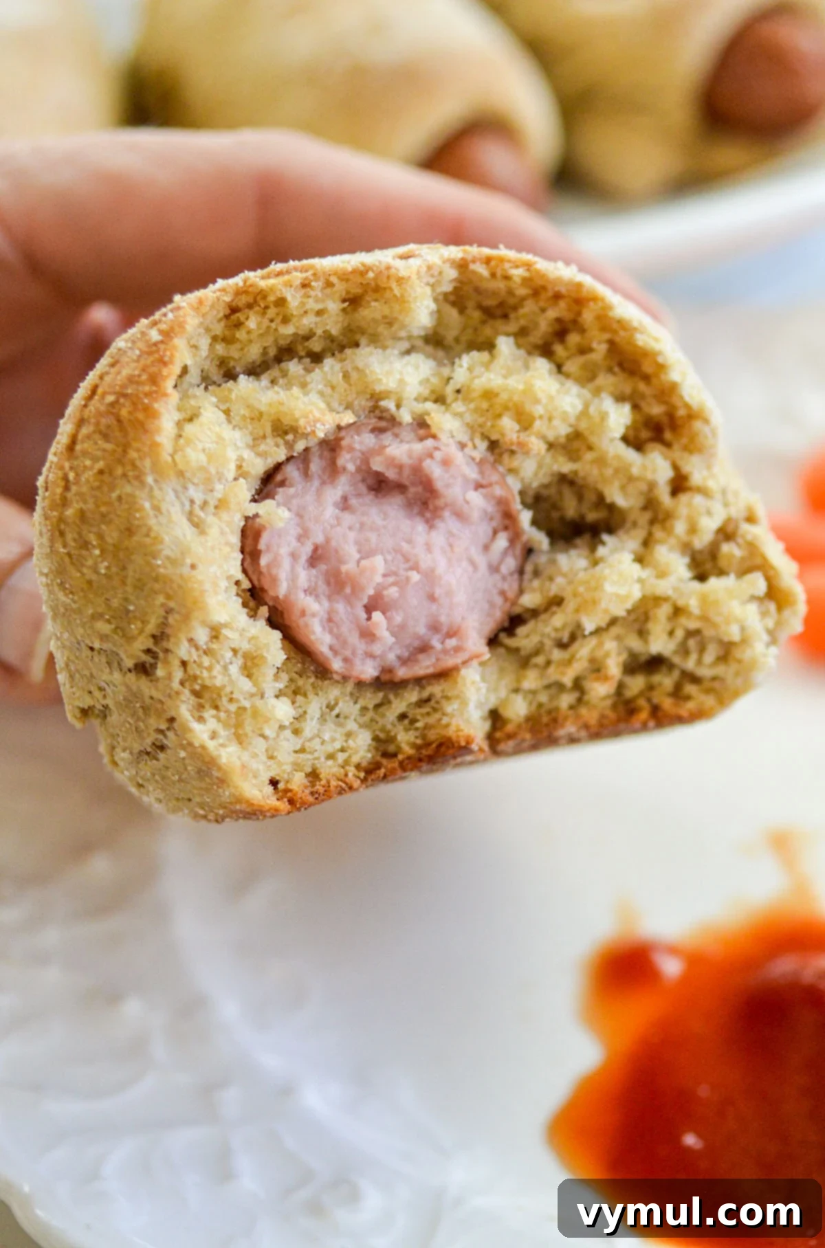 Easy 1-Hour Homemade Pigs In a Blanket 10 A baked pigs in a blanket cut in half, revealing the juicy hot dog and the soft, fluffy homemade dough inside.