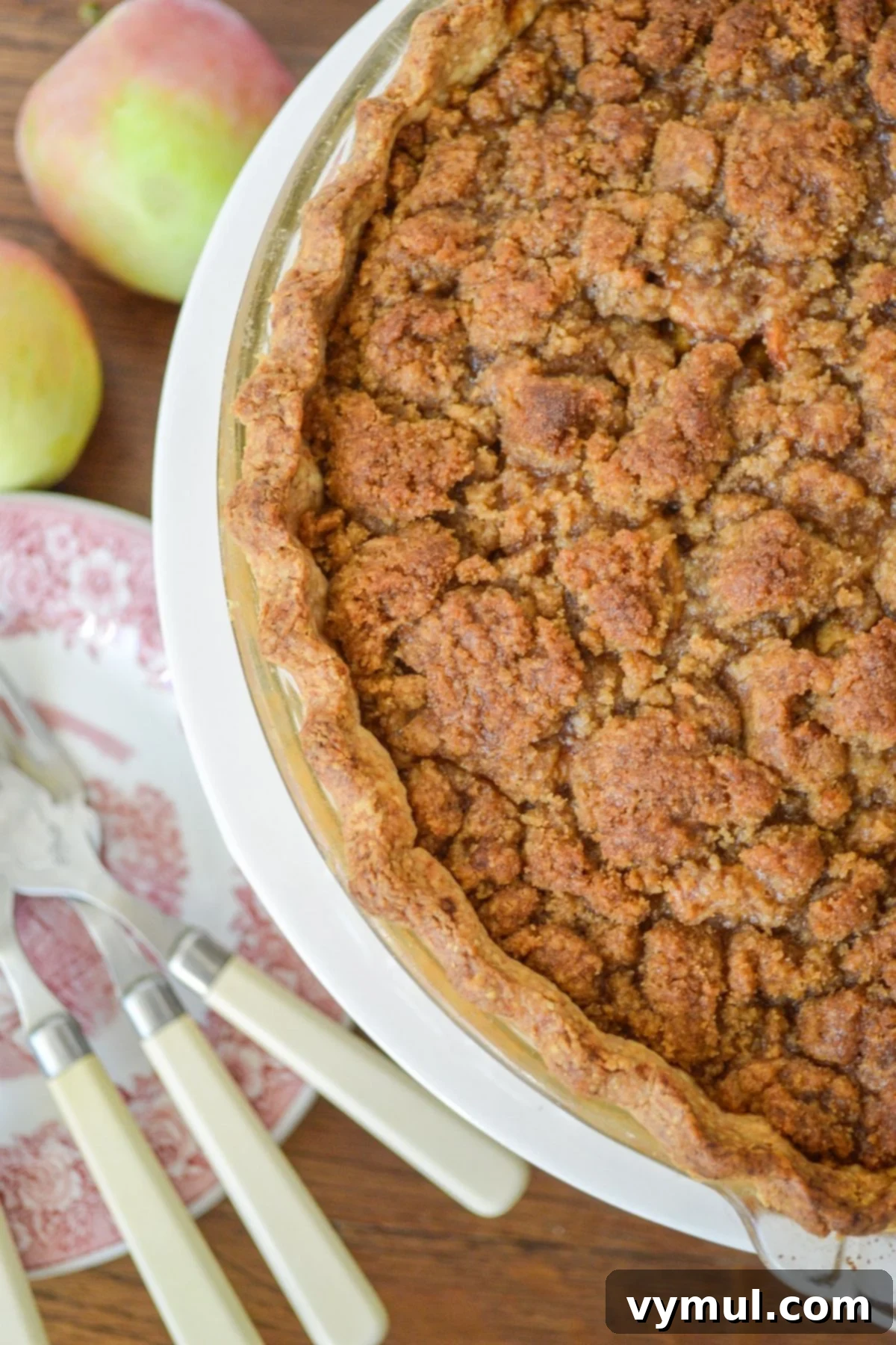 Browned crumb topped apple pie from above with plates and forks