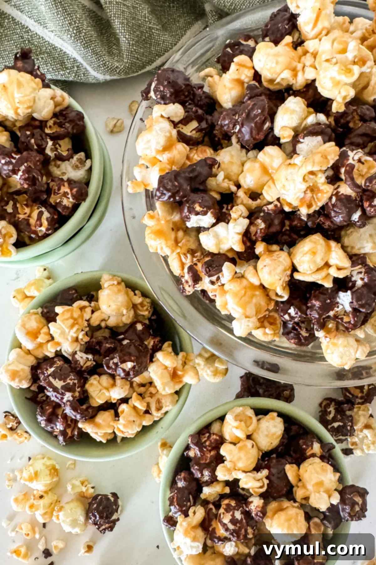 Foolproof Moose Munch Caramel Corn No Corn Syrup No Thermometer 2 Green and clear bowls brimming with homemade caramel corn and chocolate Moose Munch, a delightful no-corn-syrup snack perfect for parties and gifting.