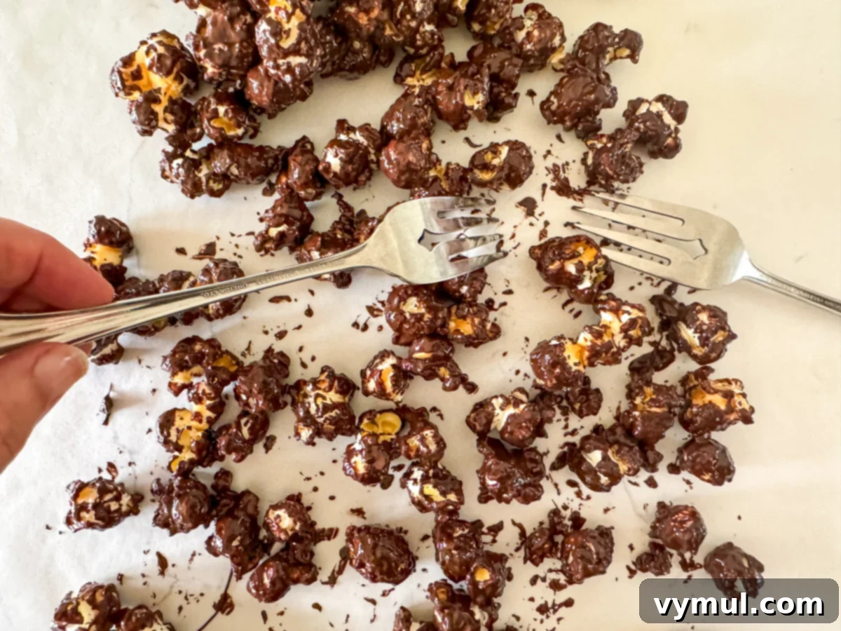 Foolproof Moose Munch Caramel Corn No Corn Syrup No Thermometer 12 Chocolate-coated caramel corn being separated on waxed paper using two forks for individual pieces.