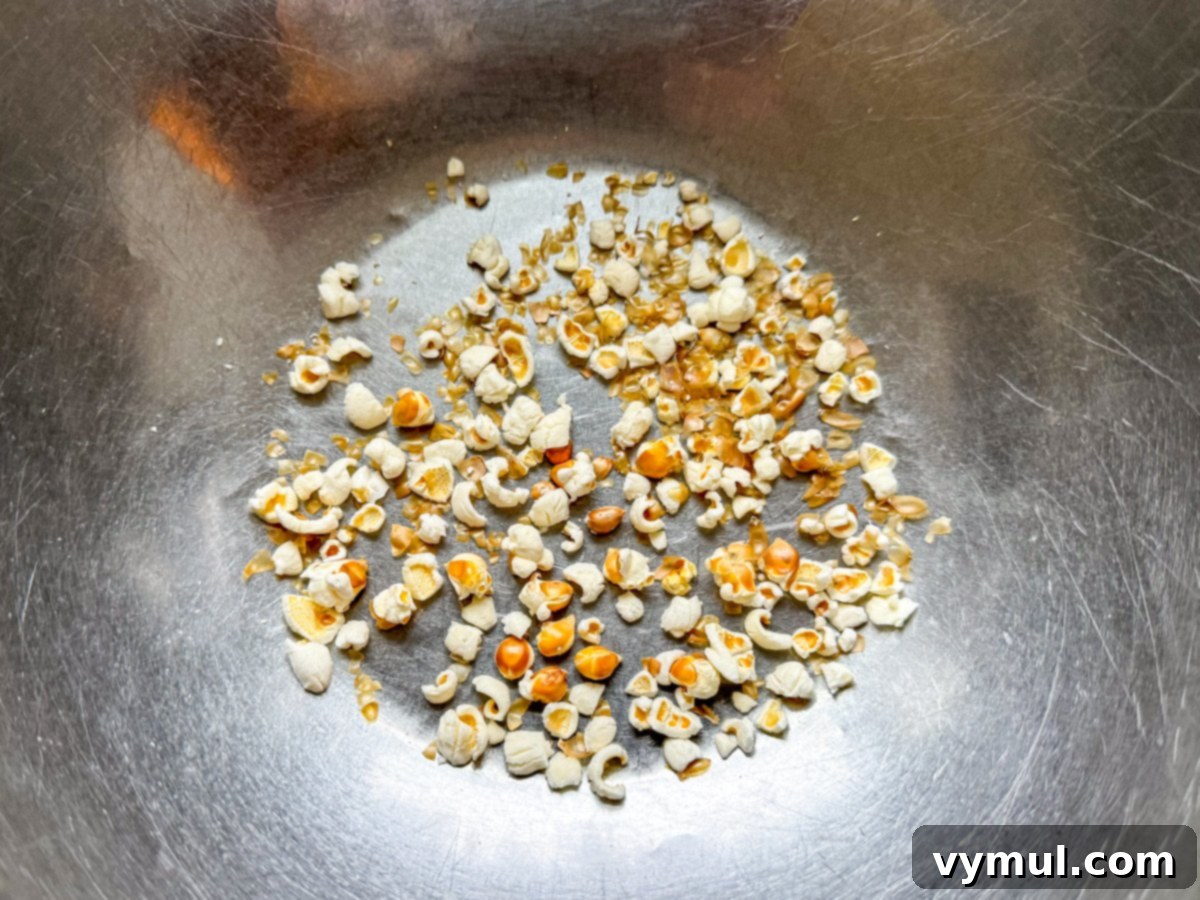 Foolproof Moose Munch Caramel Corn No Corn Syrup No Thermometer 5 Close-up of unpopped and partially popped kernels left behind in a bowl, emphasizing the importance of removing them.