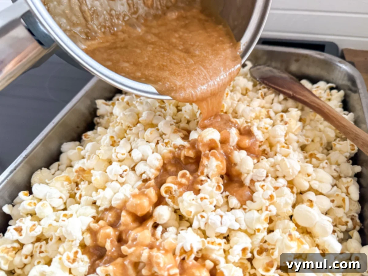 Foolproof Moose Munch Caramel Corn No Corn Syrup No Thermometer 8 Hot honey caramel being poured over warm popcorn in a roasting pan, ready for coating.