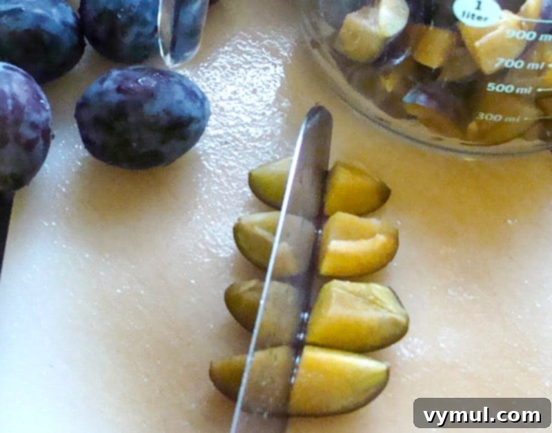 Chopping plums with a knife on a cutting board