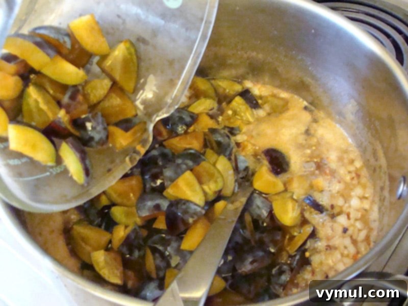 Adding chopped plums to a large pot with other ingredients
