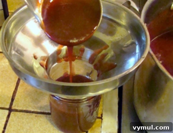 Carefully adding hot plum sauce to a canning jar