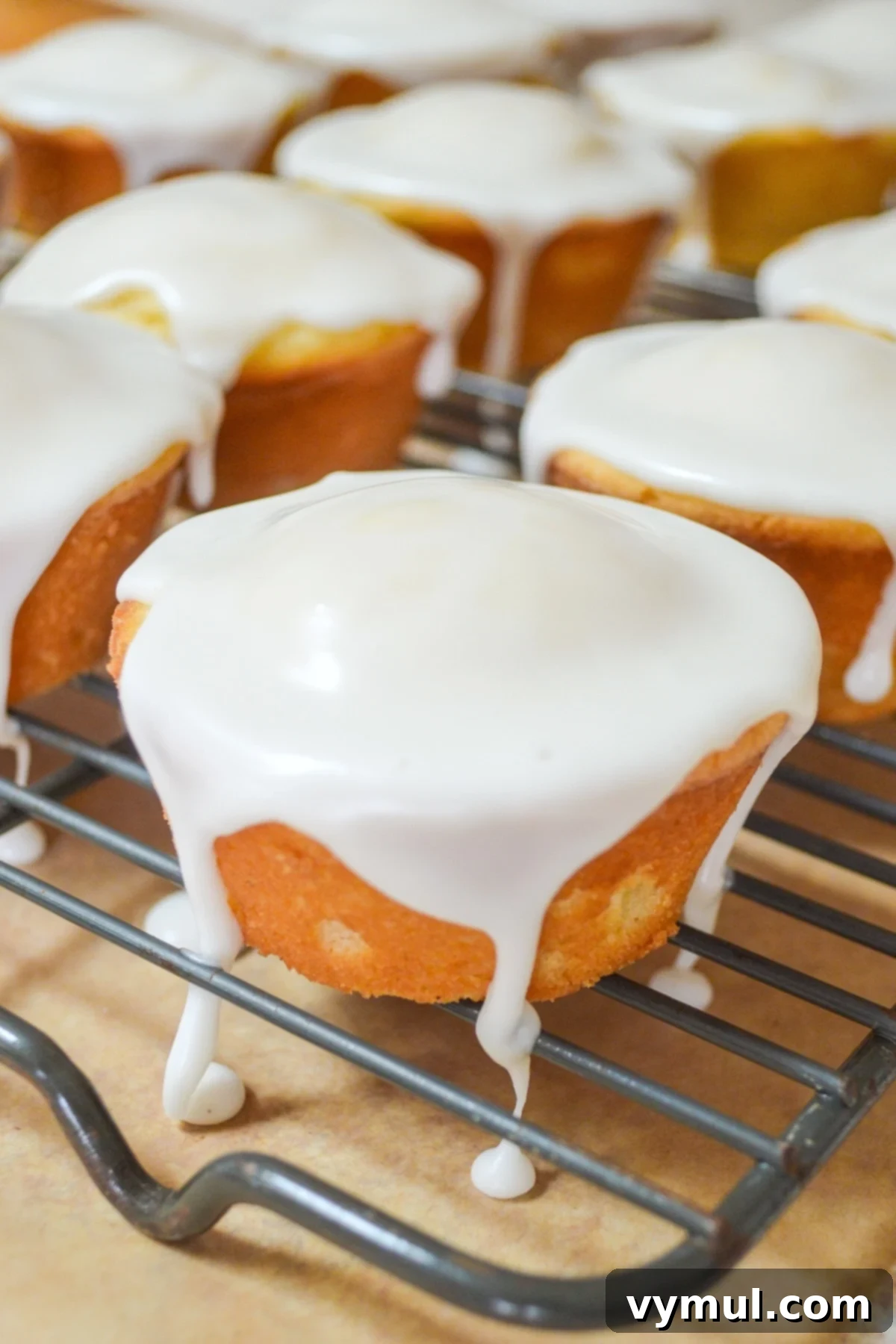 Luscious Lemon Cupcakes with a Sweet Glaze Drizzle 2 glazed lemon cupcakes on metal rack