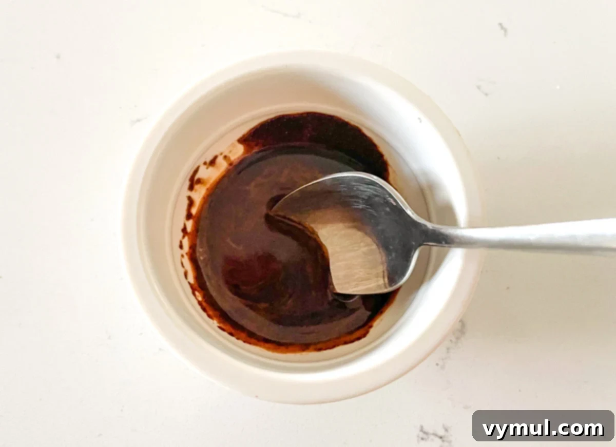 Instant espresso powder dissolving in hot water in a small cup.