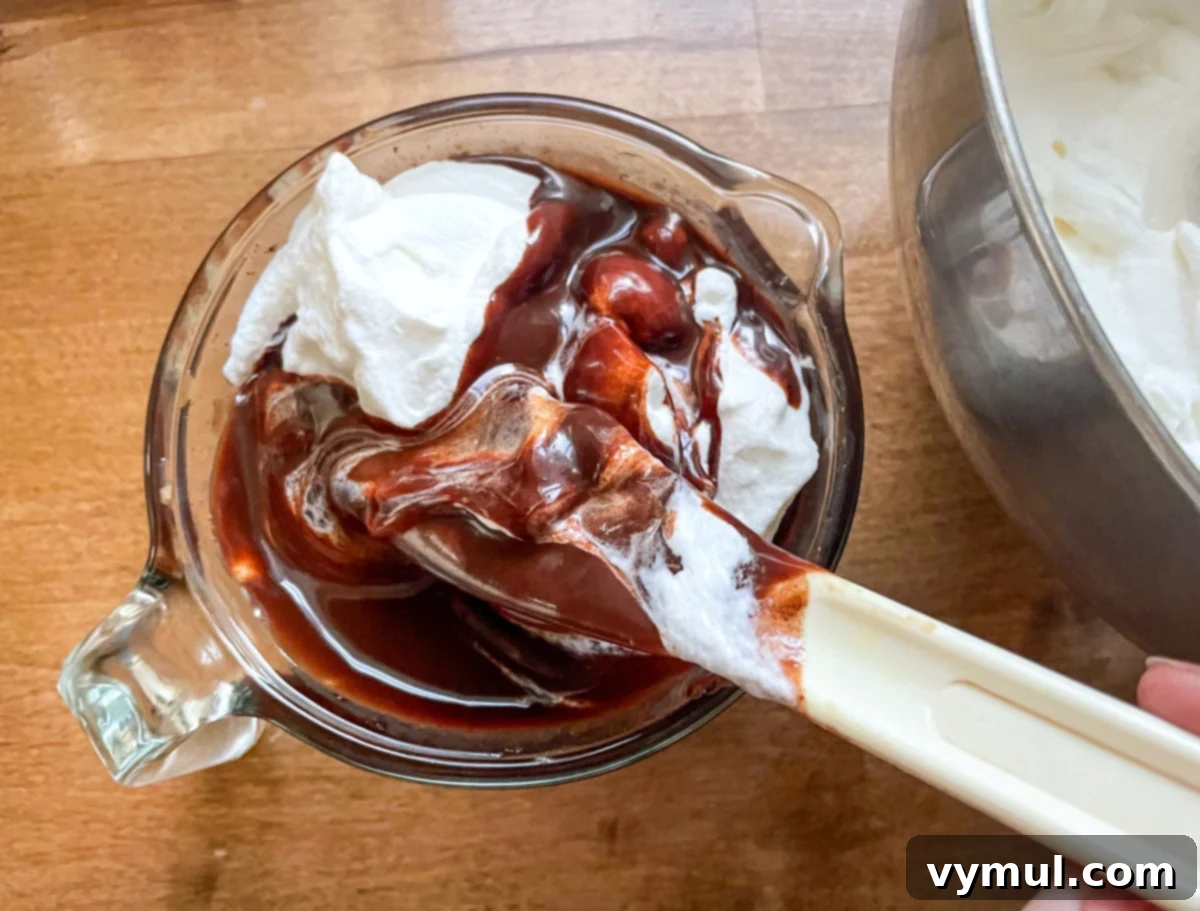 A portion of whipped cream being gently mixed into the cooled chocolate mixture.