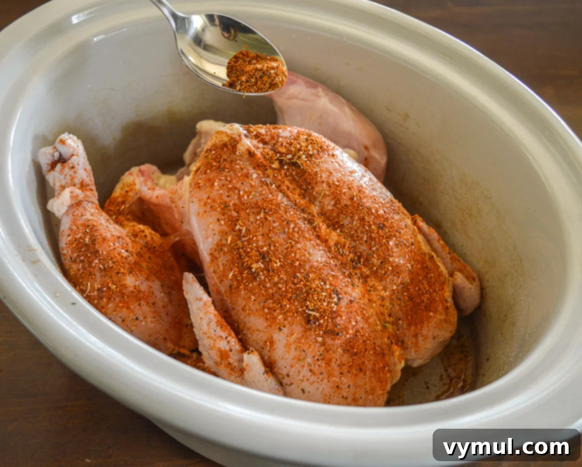 sprinkling spice mix on raw, skinned chicken in slow cooker