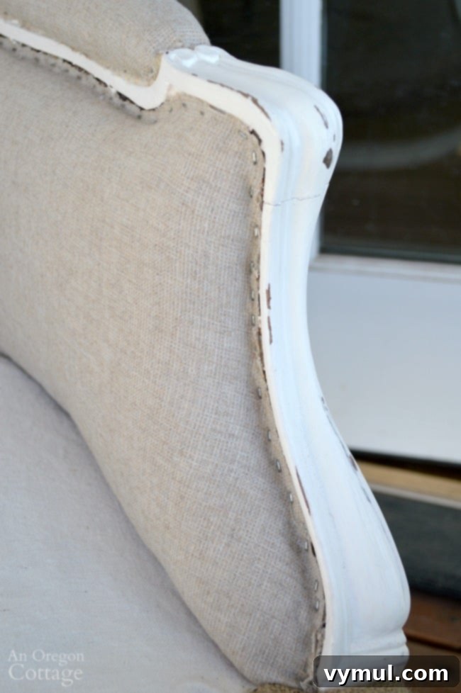 Detailed view of a distressed painted French chair arm after upholstery