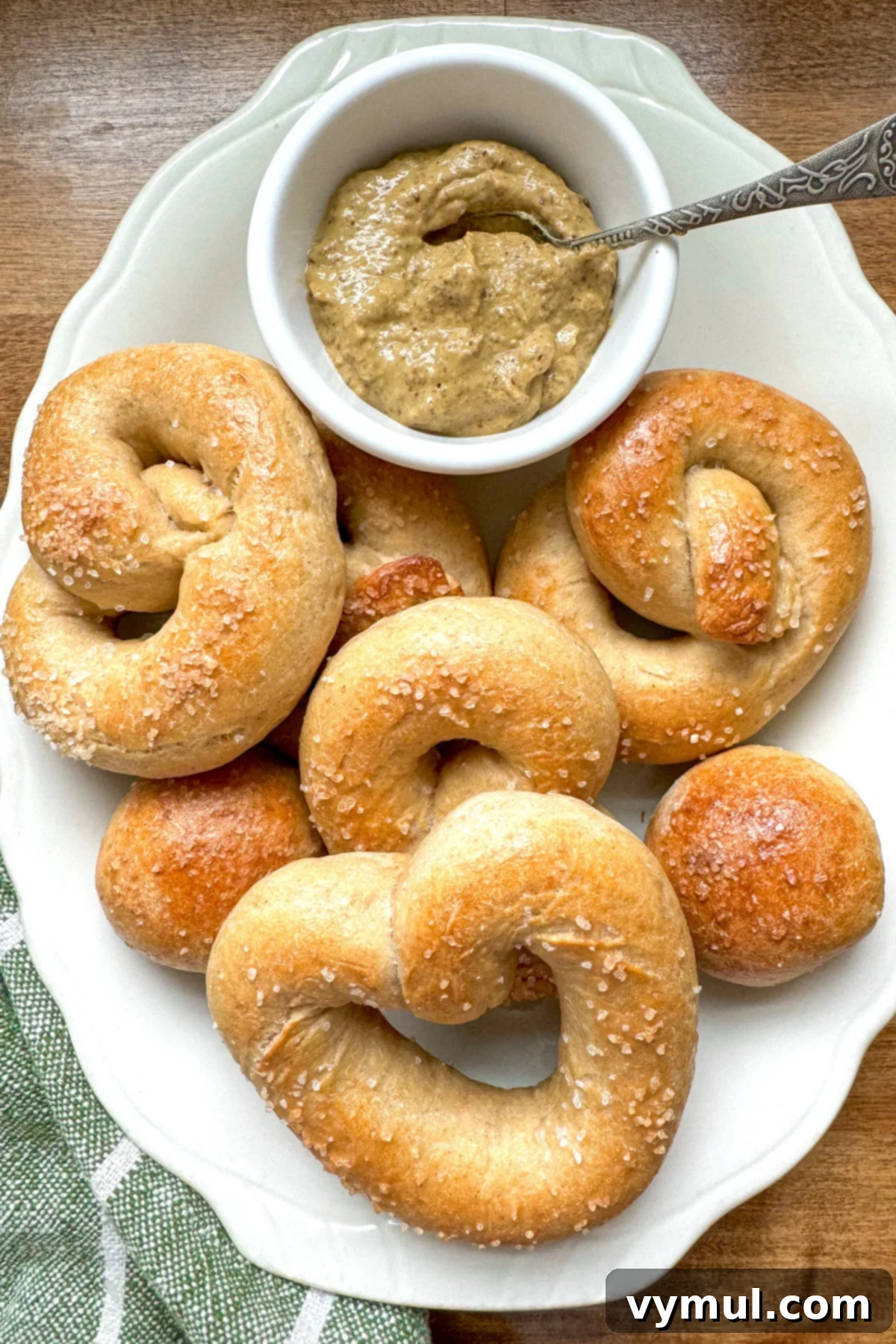 Homemade Soft Pretzels: Quick and Easy in 30 Minutes 2 shaped, baked soft pretzels on a white platter with mustard for dipping