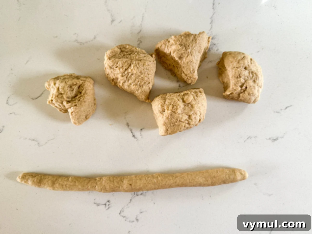 Homemade Soft Pretzels: Quick and Easy in 30 Minutes 6 pieces of pretzel dough with one rolled into a long log ready for shaping