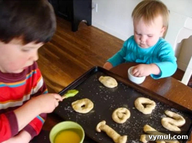 Homemade Soft Pretzels: Quick and Easy in 30 Minutes 10 4 and 2-year olds brushing egg wash and sprinkling salt on pretzel dough