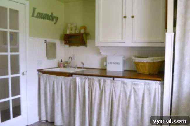 After photo of a bright and clean cottage farmhouse laundry mudroom with new flooring and painted cabinets.