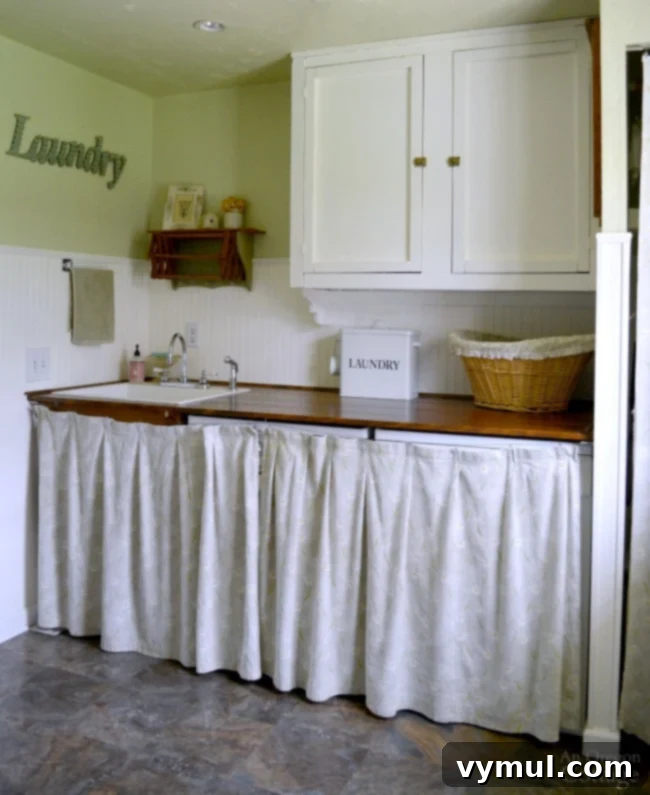 Completed cottage farmhouse laundry area with sink, washer-dryer, organized counter, and a hidden drying closet.