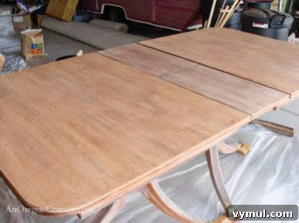 sanded dining table-step1: A close-up view of a dining table top after the initial finish removal and sanding, revealing the raw wood surface.