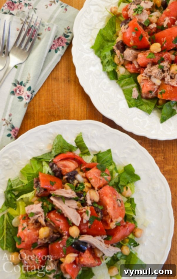 Greek Tuna Tomato Delight 3 Two plates of Greek Tuna Tomato Salad, artfully arranged to highlight the fresh, colorful ingredients like red tomatoes, dark olives, and white feta cheese.